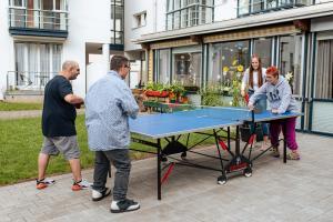 Pädagogische Fachkraft spielt mit drei Klient*innen Tischtennis