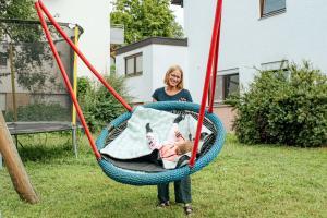 Pädagogische Fachkraft lässt Kleinkind schaukeln