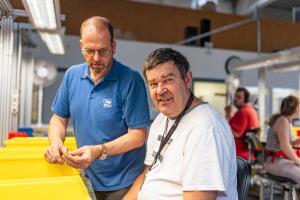 Arbeitserzieher mit Klient im Arbeitsbereich einer Werkstatt